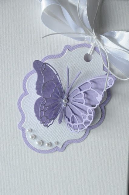 a purple and white butterfly hanging from the side of a door with a ribbon on it