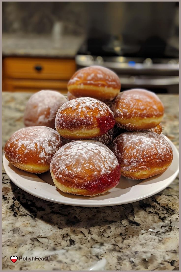 a white plate topped with donuts covered in powdered sugar on top of a counter