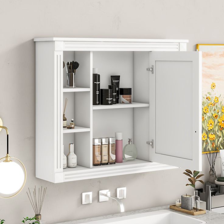 a white bathroom cabinet with various items on the shelf and sink in front of it