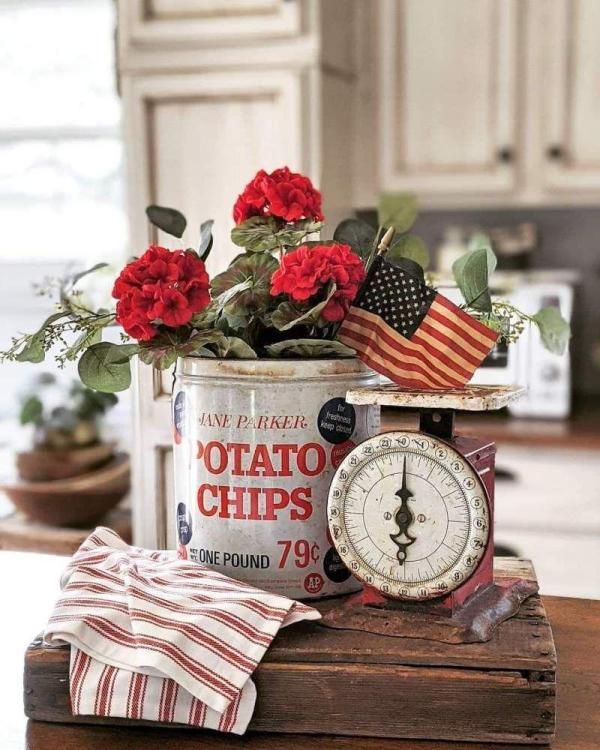 an old tin can with red roses in it sitting on top of a wooden table