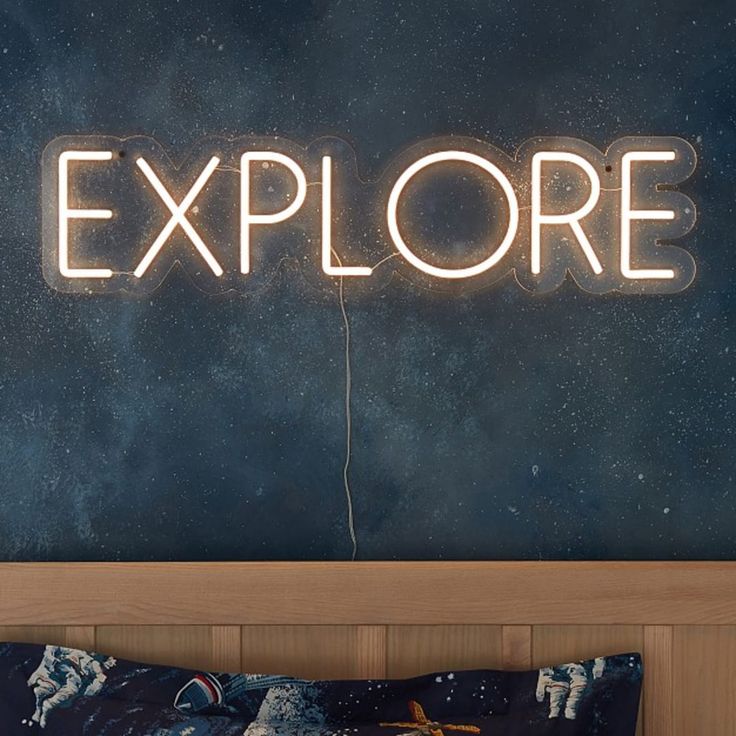 a neon sign that reads explore above a bed