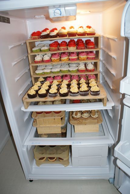 an open refrigerator filled with lots of different types of cupcakes and muffins