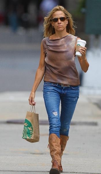 a woman walking down the street with a starbucks cup in her hand