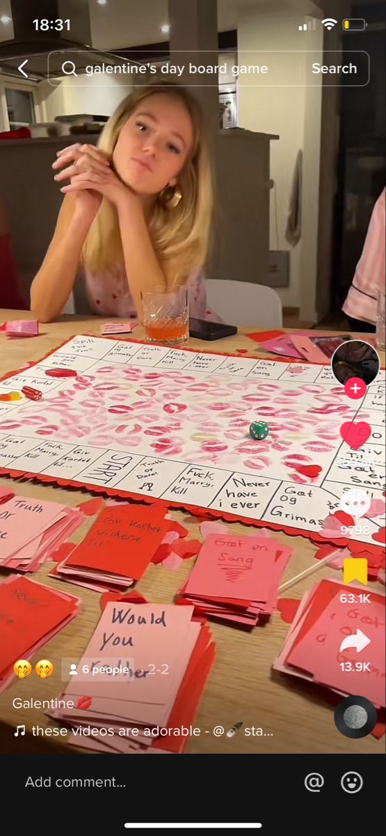 a woman sitting at a table with pink and red cards on top of it,