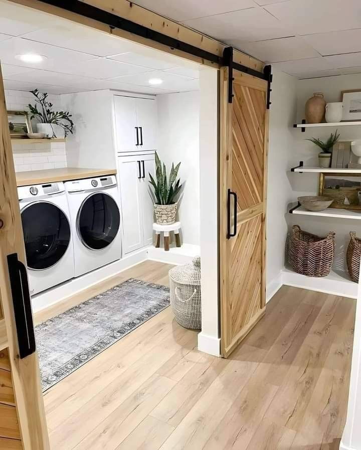 a washer and dryer in a room with wooden floors, white walls and open doors