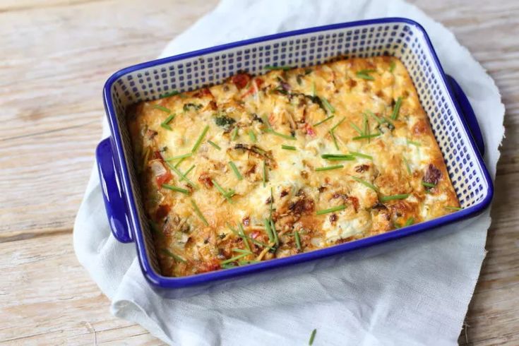 a casserole dish with vegetables in it on a napkin next to a wooden table