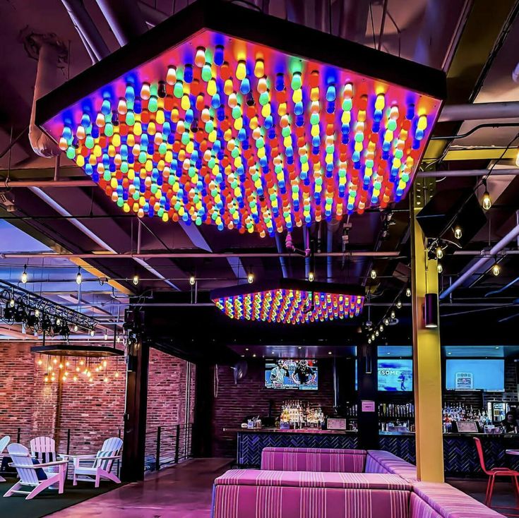 a room filled with lots of colorful lights hanging from it's ceiling and chairs