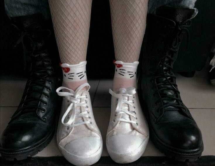 the legs and feet of two people wearing black shoes with white laces on them