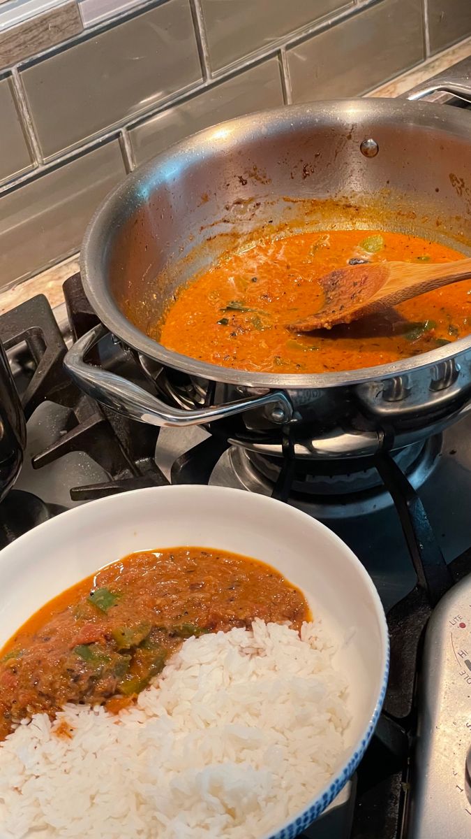 two bowls of food sitting on top of a stove next to a pan filled with rice