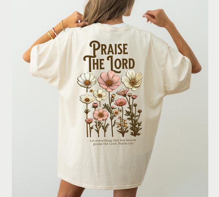 a woman wearing a white t - shirt that says praise the lord with flowers on it