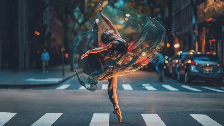 a woman is dancing on the street with her arms in the air and legs spread out