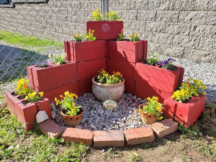 a small garden area made out of red bricks and plants in pots on the ground