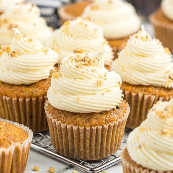 cupcakes with white frosting and sprinkles are on a cooling rack