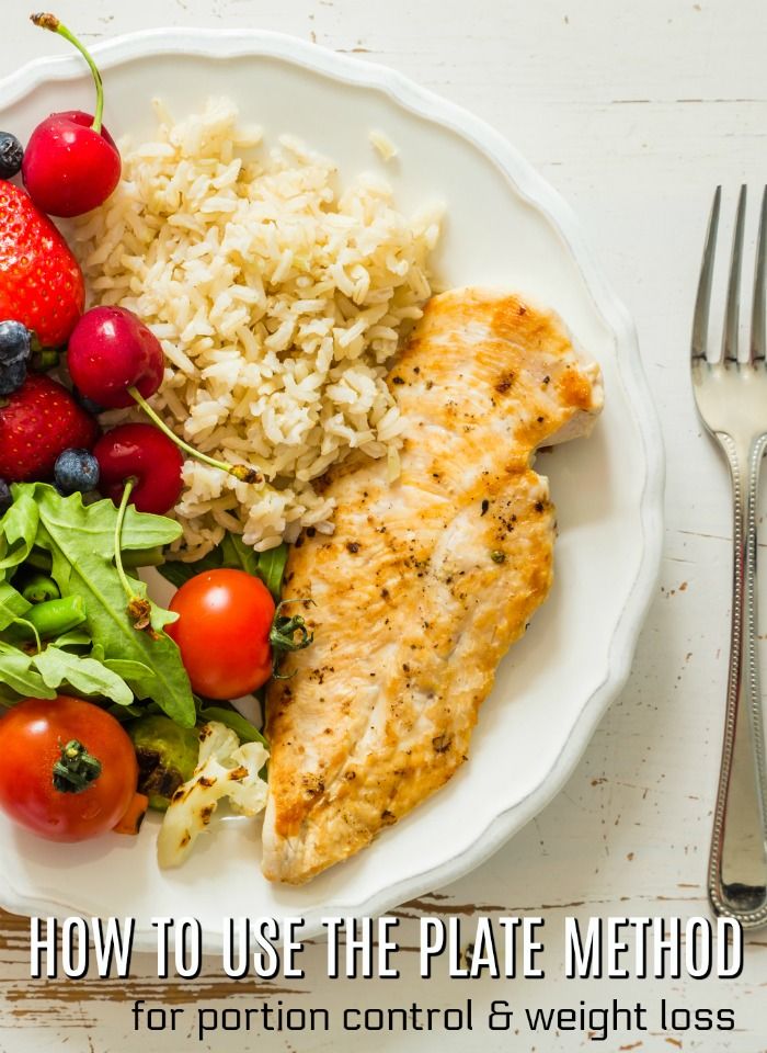 a white plate topped with chicken, rice and berries next to a fork and knife