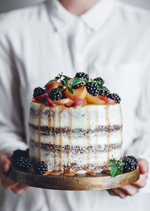 a person holding a cake with fruit on top