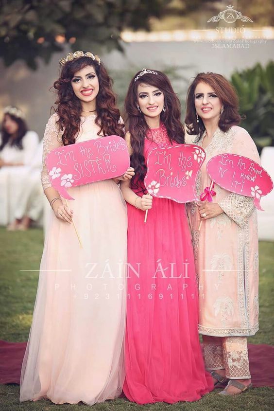 three women in long dresses holding signs that say i love you and one is wearing a tiara