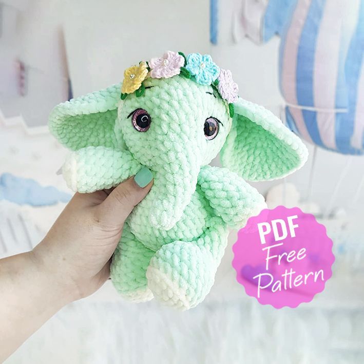 a hand holding an elephant stuffed animal with flowers on it's head and the words free pattern below