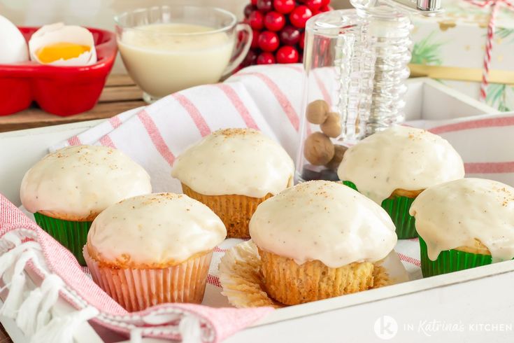 cupcakes with white frosting in a box on a table next to other ingredients