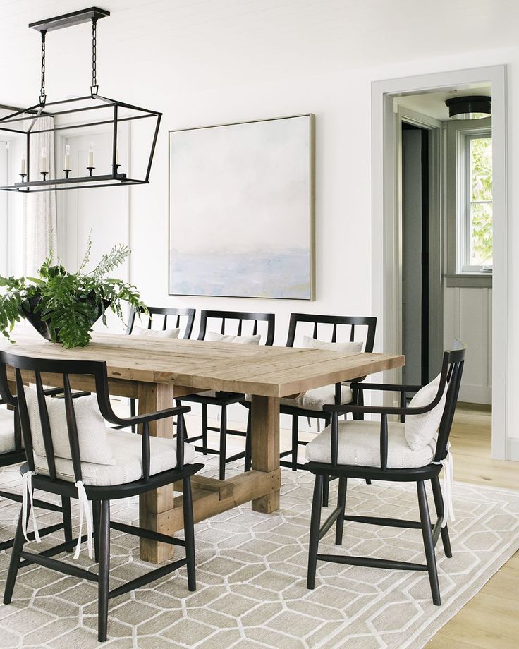 the dining room table is made from wood and has white upholstered chairs with black legs