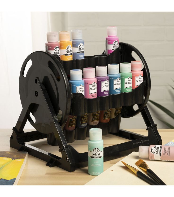 an art supply stand with many different colors of paint on it and some brushes next to it