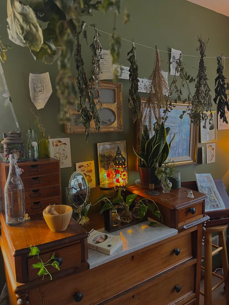 a desk with plants and pictures on the wall above it, along with other items