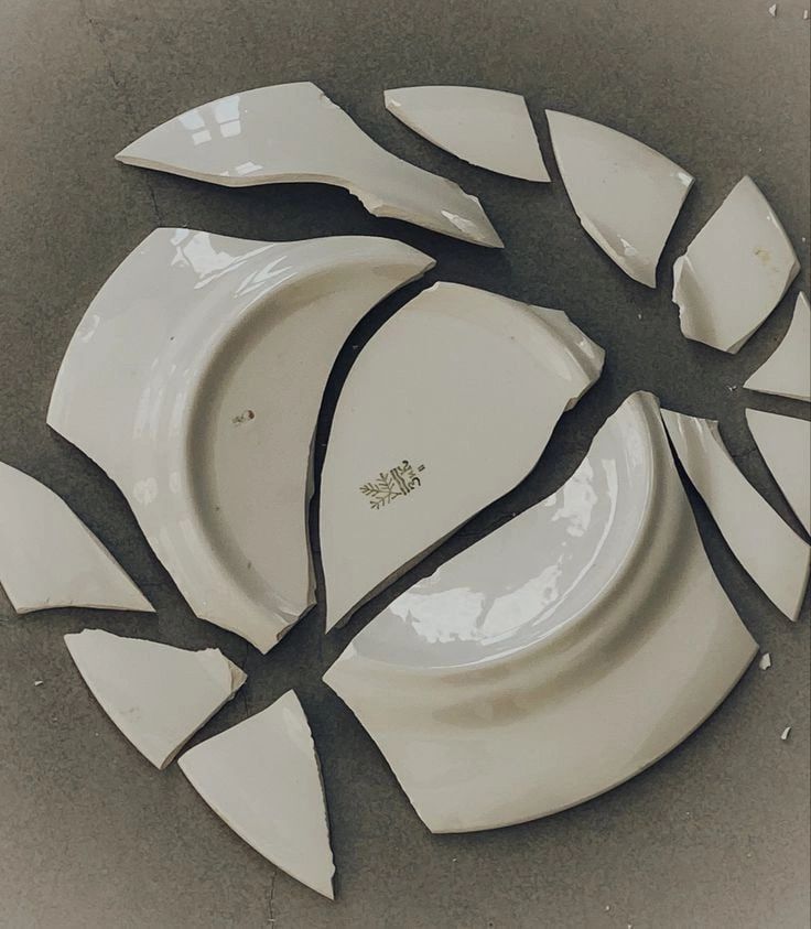 a broken white plate sitting on top of a table