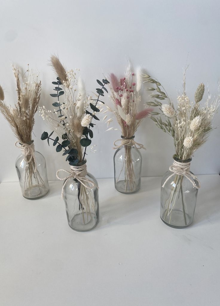 four vases with dried flowers and plants in them