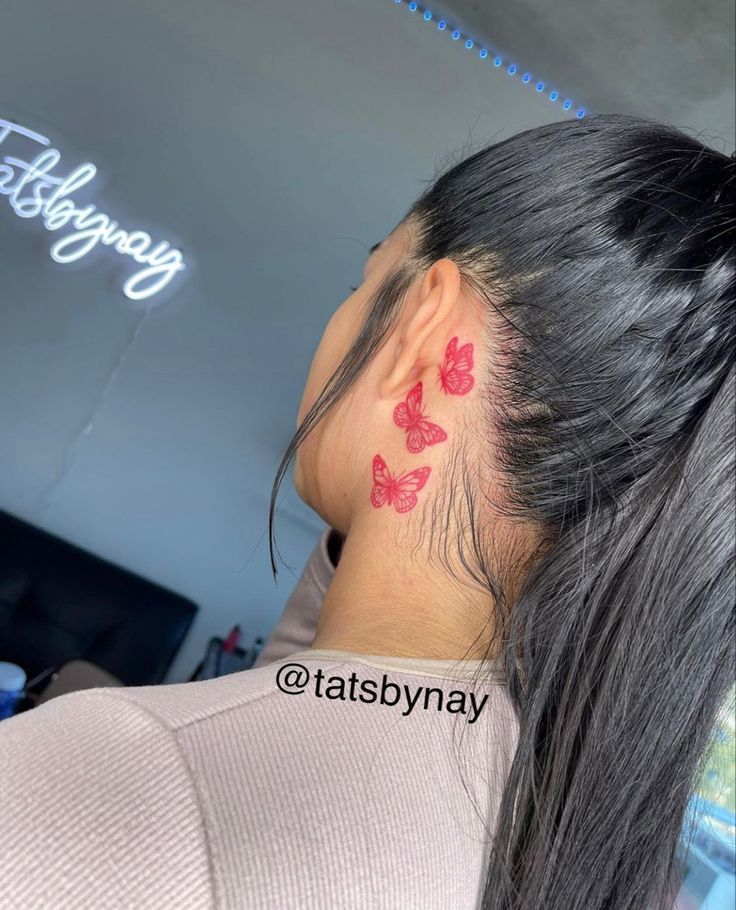 a woman with a red butterfly tattoo on her left side of her neck and behind her ear