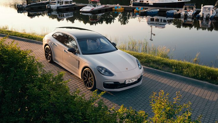 a white sports car parked on the side of a road next to a body of water