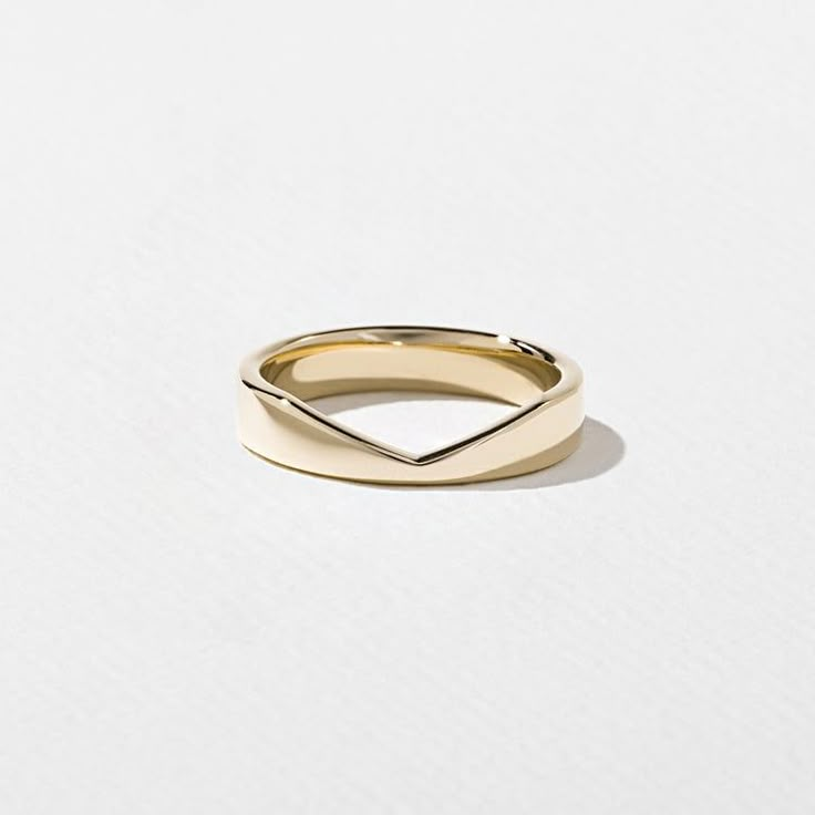 a gold ring with an irregular design on the top and bottom, sitting on a white surface