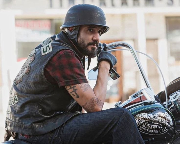 a man sitting on top of a motorcycle wearing a helmet and holding the handlebars