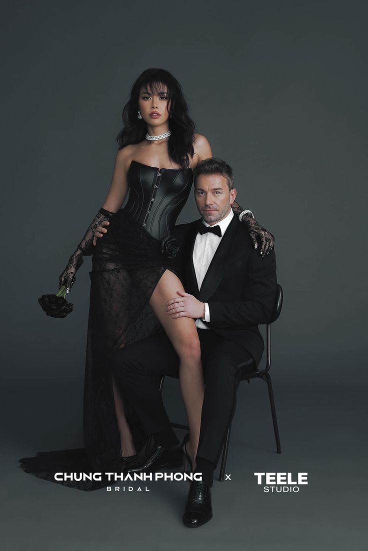 a man sitting next to a woman in a black dress on top of a chair