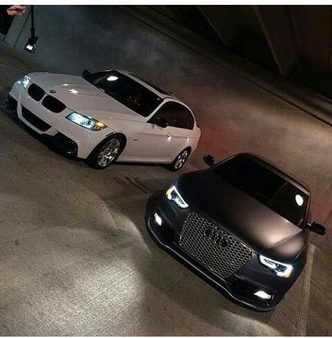 two black and white cars parked next to each other in an underground parking lot at night