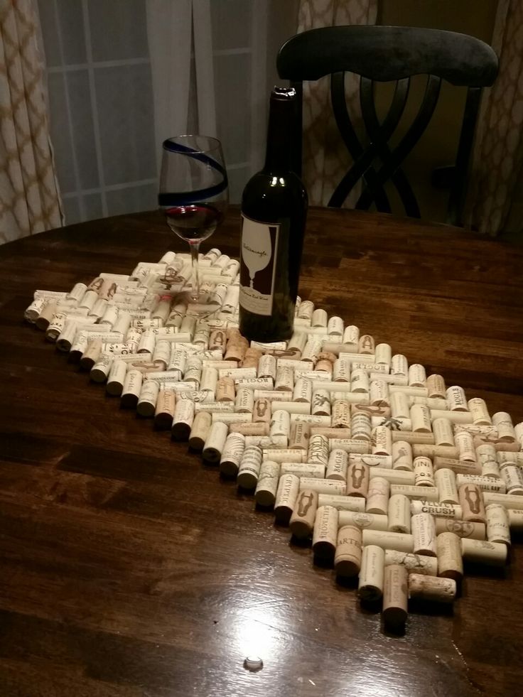 a wine bottle sitting on top of a wooden table next to a cork mat that is shaped like a cross