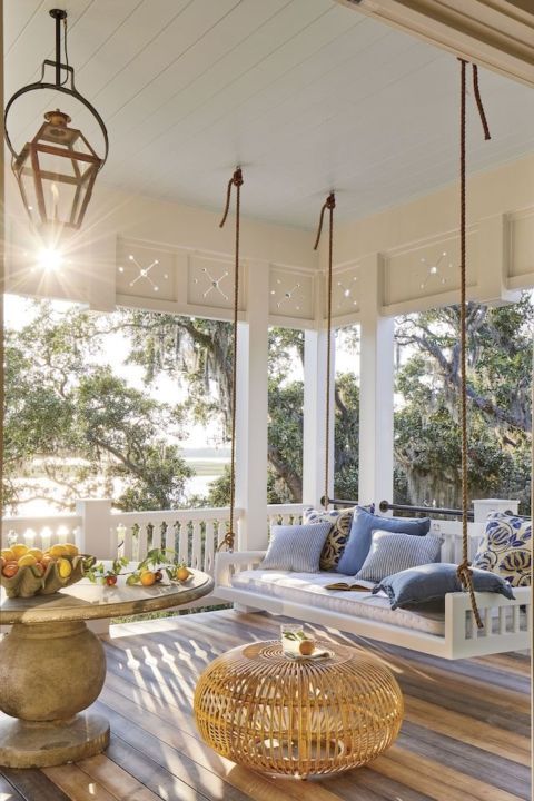 a porch with wooden floors and hanging chairs on the front porch, surrounded by large windows