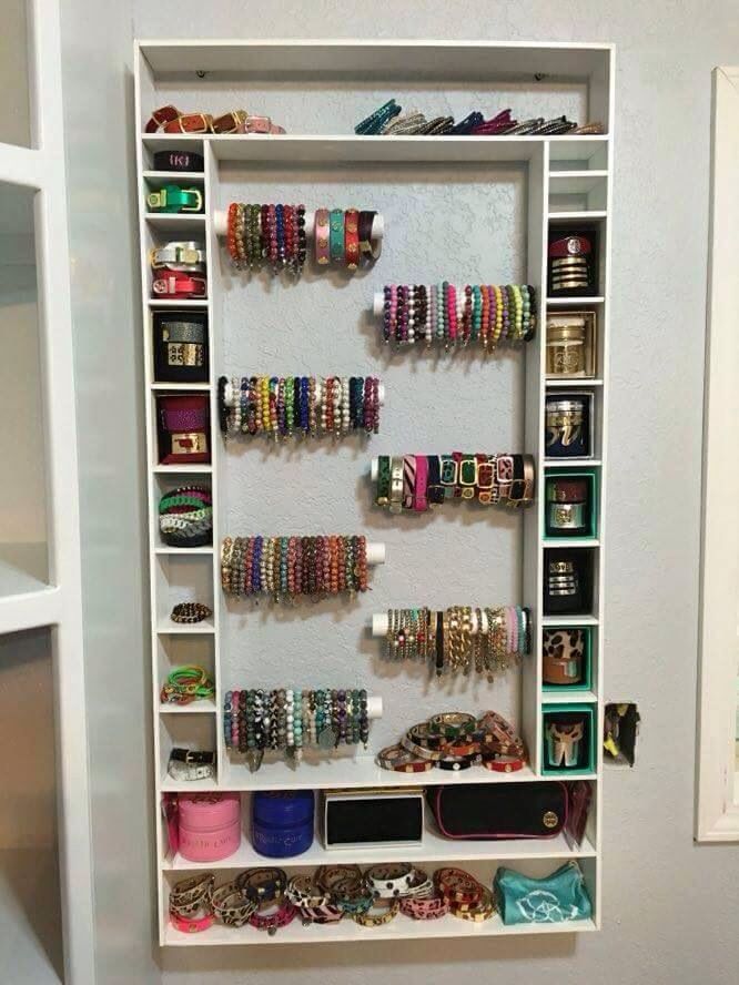 a white wall mounted jewelry rack filled with lots of bracelets