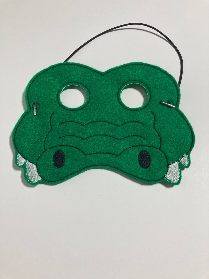 a green mask with two holes in the middle and an alligator's head on it