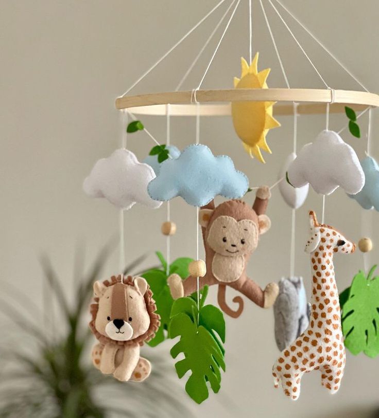 a crib mobile with stuffed animals hanging from it's sides and clouds in the background