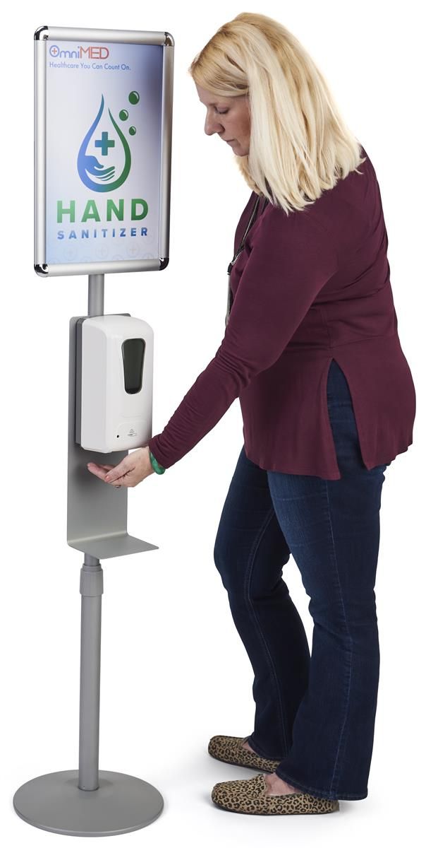 a woman standing next to a sign that says hand sanitizer on the screen