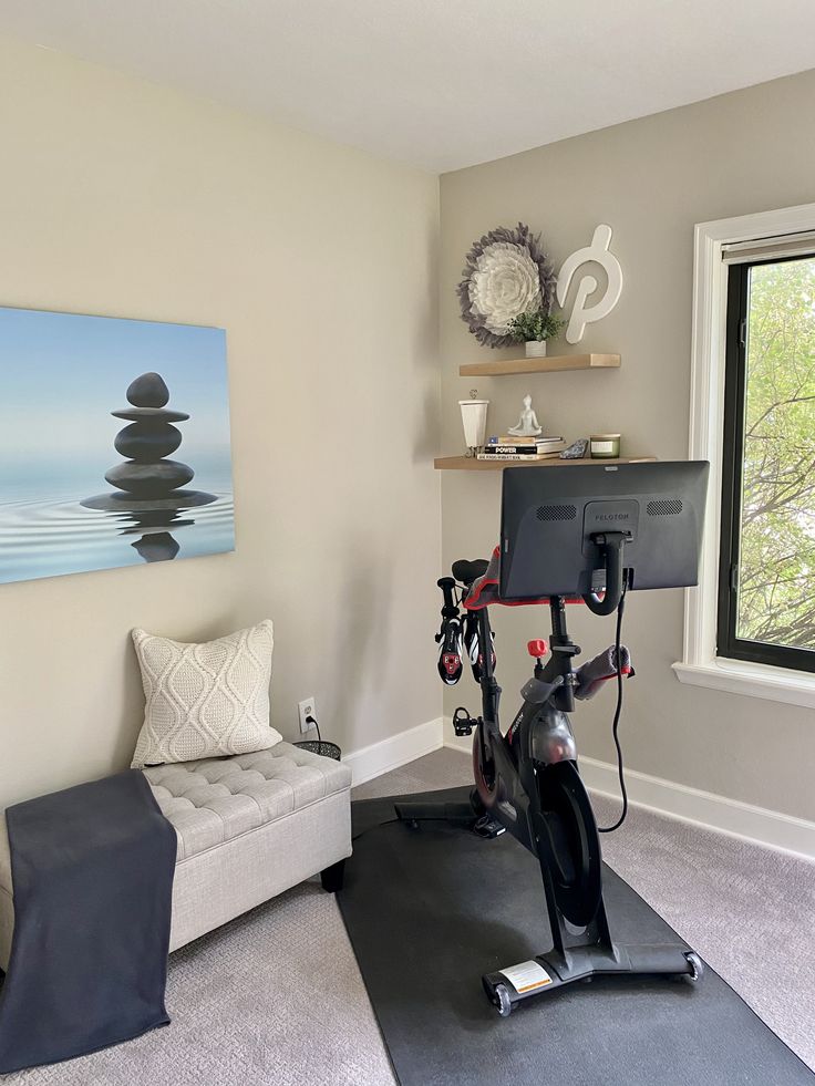 an exercise room with a bike, couch and window in the backround area