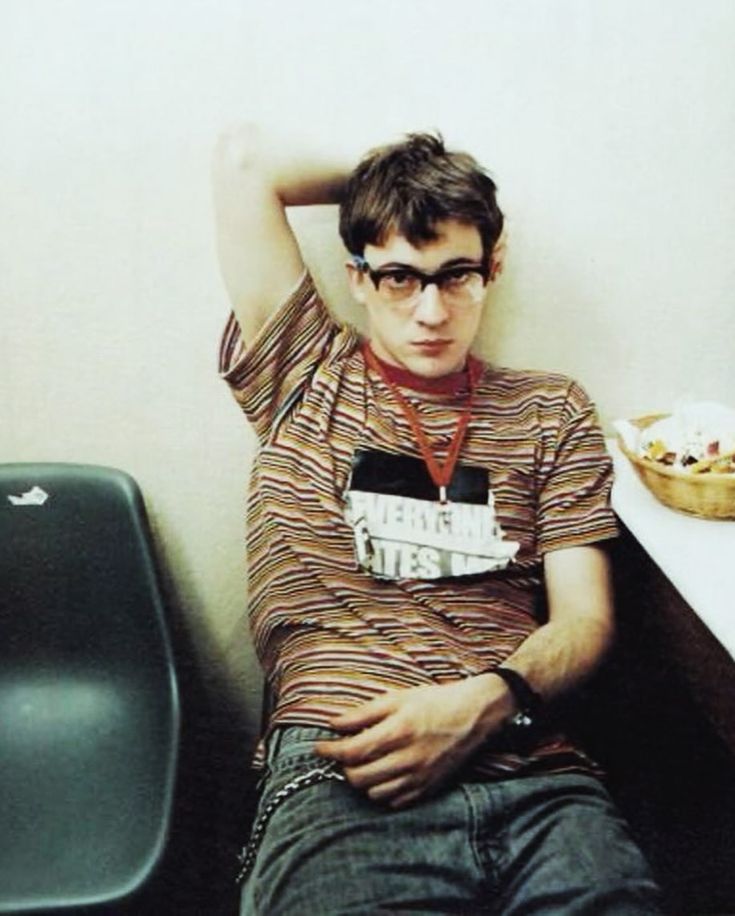 a young man sitting next to a trash can