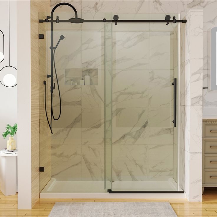 a bathroom with a glass shower door and white rugs on the wooden flooring