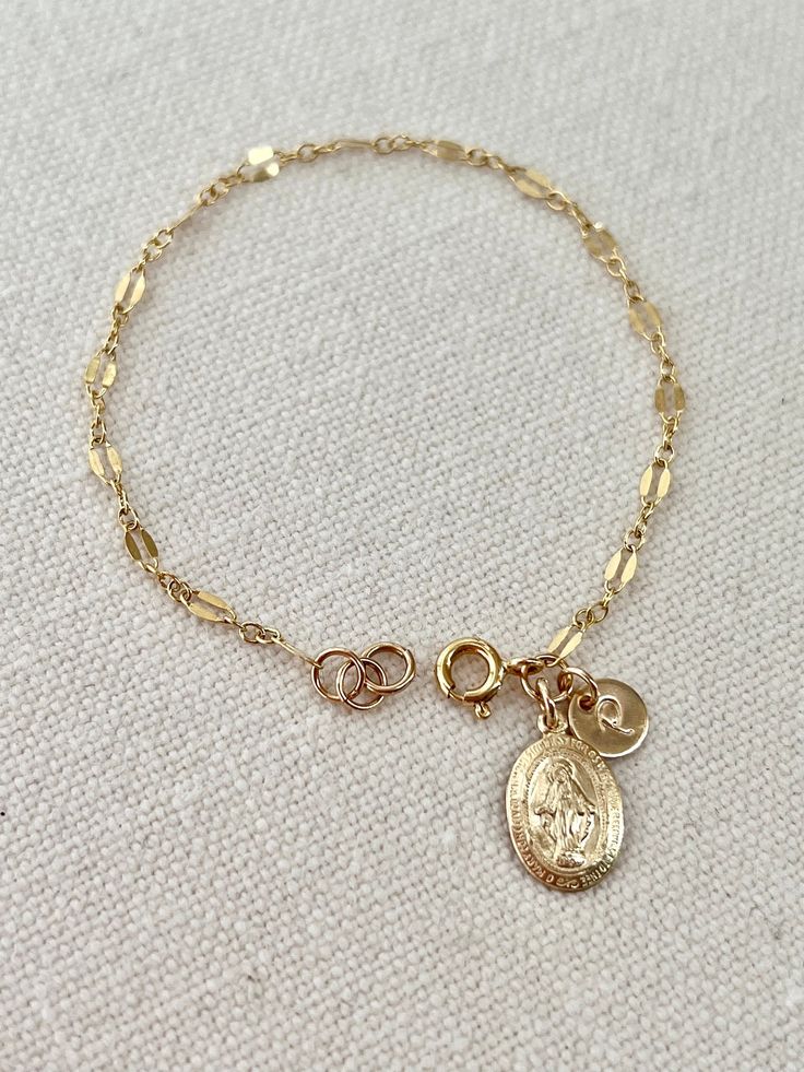 Virgin Mary bracelet, personalized bracelet, meaningful gift for yourself or the people you love. Details. - Miraculous medal 13 x 9 mm. - Sturdy chain genuine 14 k gold filled. - Disk 6.5 mm. - Elegant or script uppercase font. - All components are 14 k gold filled, quality mark. - Ethically sourced. - Your style, our design. Thank you very much for visiting my shop. Nickel-free Round Rosary Bracelet Gift, Personalized Gold Rosary Bracelet As Gift, Spiritual Chain Bracelet With Charms As Gift, Nickel Free Spiritual Chain Bracelet Gift, Nickel-free Spiritual Chain Bracelet Gift, Spiritual Charms Chain Bracelet For Gift, Oval Link Charm Bracelet As Gift, Oval Link Charm Bracelet Gift, Nickel-free Yellow Gold Charm Bracelet Gift