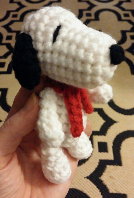 a hand is holding a small crocheted dog