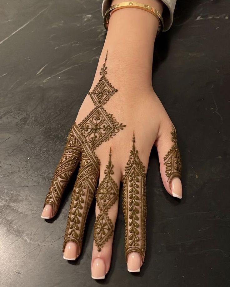 a woman's hand with henna tattoos on it