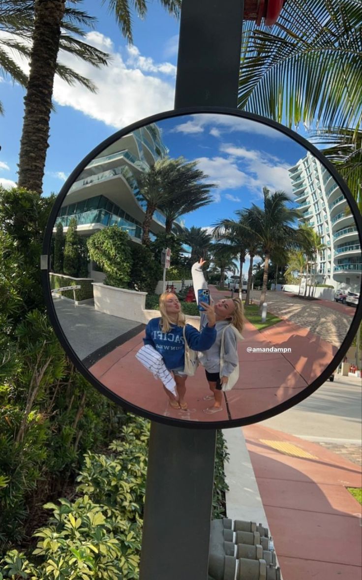 the reflection of two young boys in a round mirror on a pole near palm trees