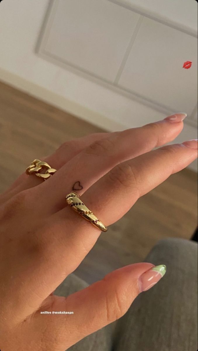 a woman's hand with two gold rings on top of her finger and one ring in the middle