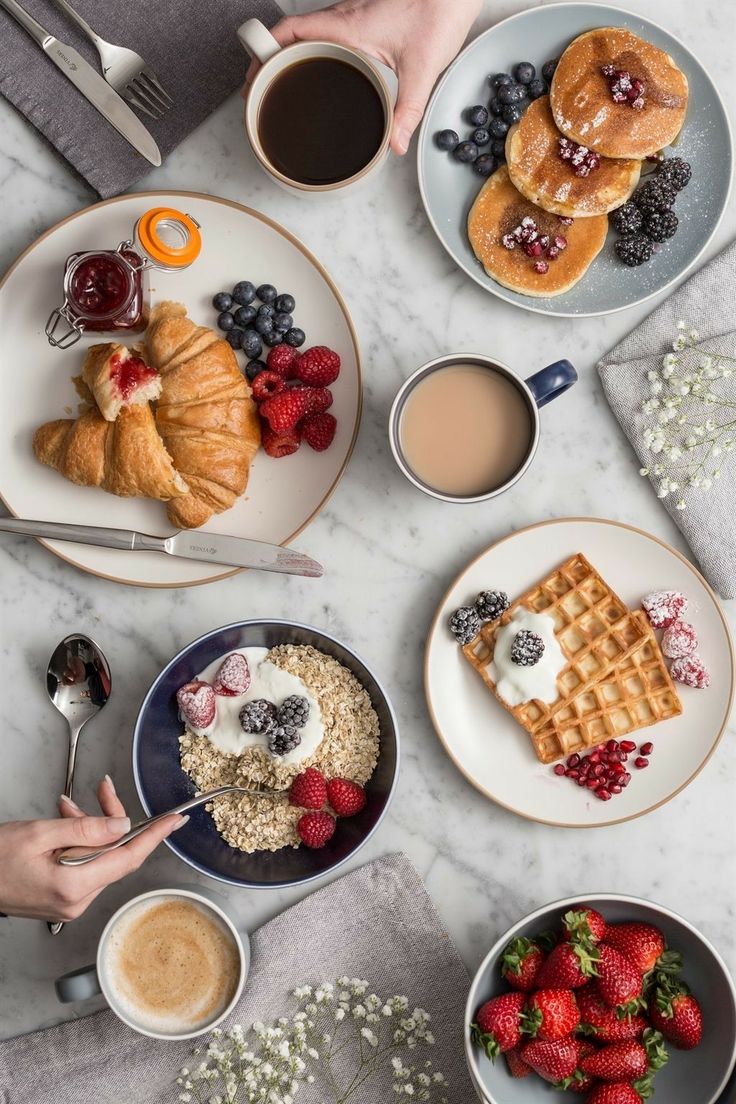 breakfast plates with croissants, strawberries, blueberries, and coffee