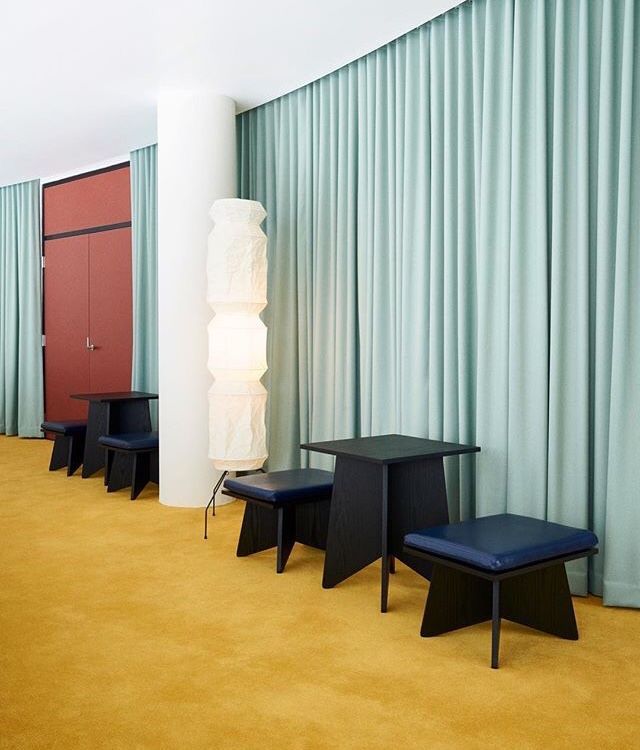 an empty room with blue and yellow drapes on the walls, two black chairs and one red chair