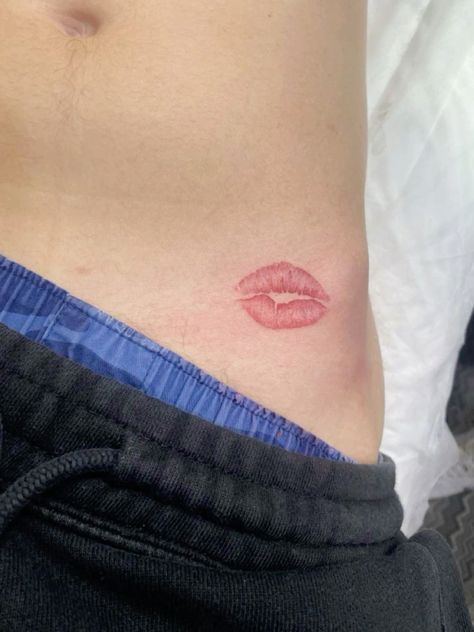 a close up of a person's stomach with a red lip tattoo on it